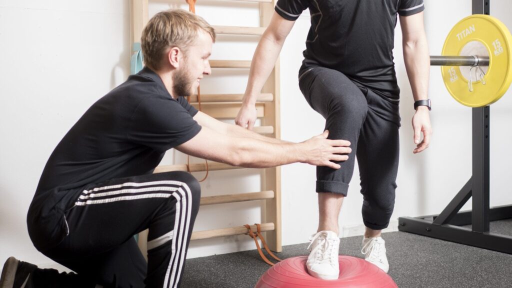Fysioterapeut træne stabilitetstræning med mand med knæsmerter